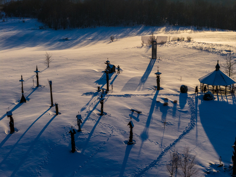 Aerial view of the Hill of Angels featuring wooden sculptures and a gazebo with long shadows on the snow covered field during sunset in Traku rajonas Vilniaus apskritis Lithuania. Aerial view of the Hill of Angels featuring wooden sculptures and a gazebo with long shadows on the snow covered field during sunset in Traku rajonas Vilniaus apskritis Lithuania.