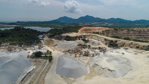 Aerial view of a gravel and sand mining site with industrial machinery and large piles of extracted materials on Karimun Island Karimun Kepulauan Riau Indonesia.