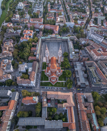 Aerial view of the Votive Church of Szeged with its twin towers and red roof situated in the historic Dom ter surrounded by urban buildings and greenery in Szeged Hungary. Aerial view of the Votive Church of Szeged with its twin towers and red roof situated in the historic Dom ter surrounded by urban buildings and greenery in Szeged Hungary.
