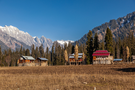 View of traditional wooden houses in the village of Arang Kel with snow capped mountains and pine trees Arang Kel Azad Kashmir Pakistan. View of traditional wooden houses in the village of Arang Kel with snow capped mountains and pine trees Arang Kel Azad Kashmir Pakistan.