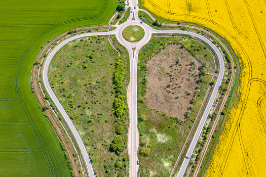 Aerial view of a heart shaped road junction with a roundabout surrounded by vibrant green and yellow rapeseed fields Ploiesti Prahova Romania. Aerial view of a heart shaped road junction with a roundabout surrounded by vibrant green and yellow rapeseed fields Ploiesti Prahova Romania.