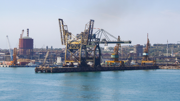 View of massive cranes stand sentinel over the harbor where deep blue waters meet industrial might under a clear sky Piombino Tuscany Italy. View of massive cranes stand sentinel over the harbor where deep blue waters meet industrial might under a clear sky Piombino Tuscany Italy.