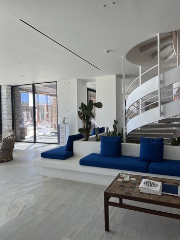 View of Hotel Tinos Suites and Apartments lobby featuring blue seating a spiral staircase and decorative cacti in Ormos Agiou Ioanni Greece.