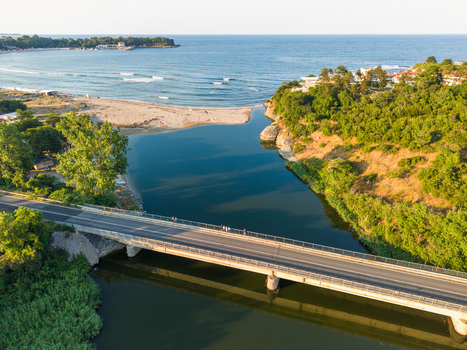 Aerial view of Kiten South Beach where the river meets the Black Sea featuring a bridge crossing the water and lush green hills in Kiten Burgas Bulgaria. Aerial view of Kiten South Beach where the river meets the Black Sea featuring a bridge crossing the water and lush green hills in Kiten Burgas Bulgaria.
