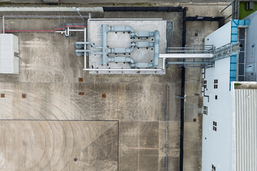 Aerial view of a data center with industrial cooling units complex piping systems and a concrete yard with tire marks in the United Kingdom.