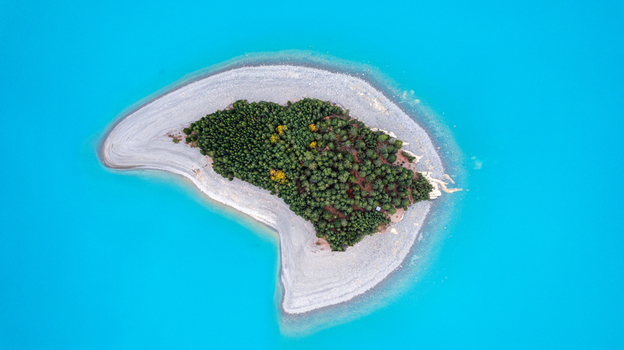 Aerial view of a small island covered in pine trees surrounded by the vibrant turquoise waters of Lake Pukaki in Twizel Canterbury Region New Zealand.
