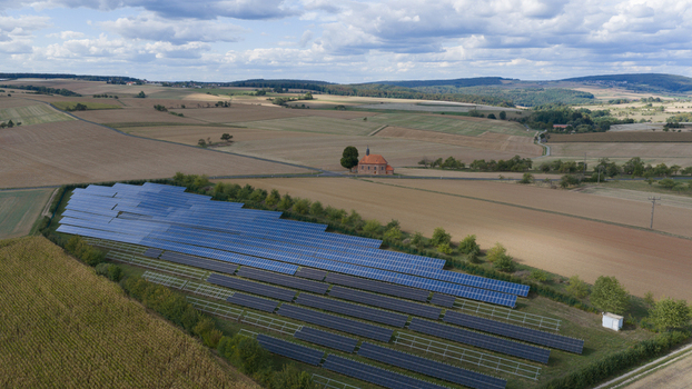 Aerial view of solar panels installed in a field near the historic Wendelinuskapelle chapel surrounded by agricultural farmland and rolling hills in Monchberg Bayern Germany. Aerial view of solar panels installed in a field near the historic Wendelinuskapelle chapel surrounded by agricultural farmland and rolling hills in Monchberg Bayern Germany.