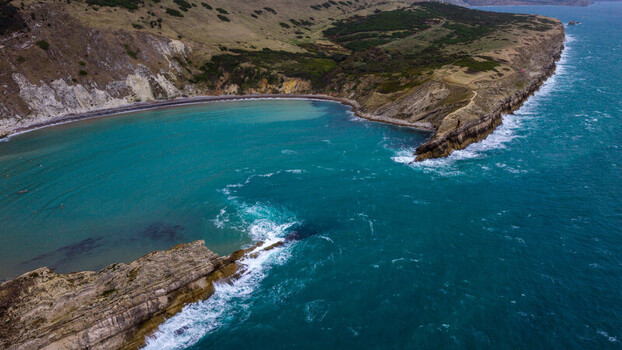 Aerial view of Lulworth Cove with its turquoise waters dramatic limestone cliffs and rugged coastline United Kingdom.