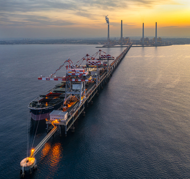 Aerial view of Orot Rabin Power Plant with a large cargo ship docked at the pier during sunset featuring industrial chimneys and calm sea waters in Hadera Haifa District Israel. Aerial view of Orot Rabin Power Plant with a large cargo ship docked at the pier during sunset featuring industrial chimneys and calm sea waters in Hadera Haifa District Israel.