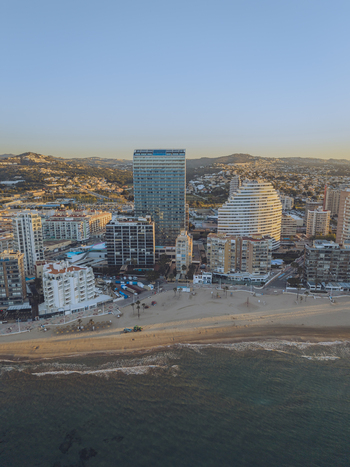 Aerial view of modern high rise buildings along the sandy coastline and calm sea in Calp Valencian Community Spain. Aerial view of modern high rise buildings along the sandy coastline and calm sea in Calp Valencian Community Spain.