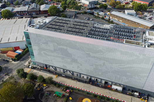 Aerial view of a modern data center building featuring a large patterned facade rooftop cooling systems and surrounding urban infrastructure in the United Kingdom. Aerial view of a modern data center building featuring a large patterned facade rooftop cooling systems and surrounding urban infrastructure in the United Kingdom.