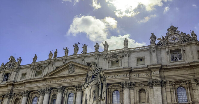 Vatican City Italy 26 September 2026 View of the facade of St. Peter s Basilica featuring the statue of Saint Peter in the foreground under a bright blue sky with clouds.