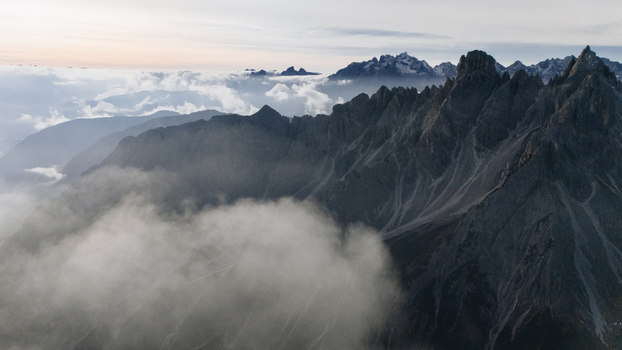 Aerial view of the jagged peaks of the Cadini group rising above a thick layer of clouds and mist in Auronzo di Cadore Veneto Italy. Aerial view of the jagged peaks of the Cadini group rising above a thick layer of clouds and mist in Auronzo di Cadore Veneto Italy.