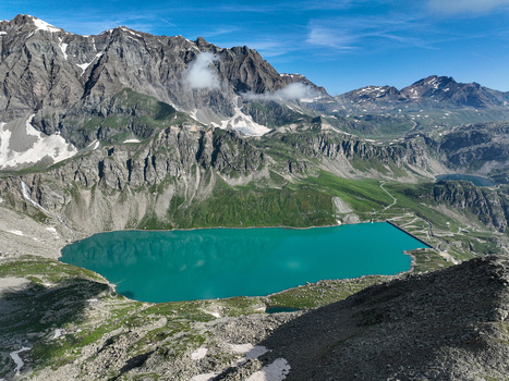 Aerial view of the turquoise Serru Lake and its dam surrounded by rugged alpine peaks and green slopes in Ceresole Reale Piedmont Italy. Aerial view of the turquoise Serru Lake and its dam surrounded by rugged alpine peaks and green slopes in Ceresole Reale Piedmont Italy.