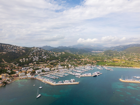 Aerial view of Port d Andratx marina with luxury yachts coastal buildings on green hills and distant mountains under a cloudy sky Port d Andratx Balearic Islands Spain. Aerial view of Port d Andratx marina with luxury yachts coastal buildings on green hills and distant mountains under a cloudy sky Port d Andratx Balearic Islands Spain.