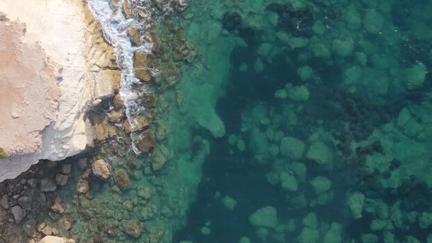 Aerial view of rocky coastline and turquoise sea in Cyprus.