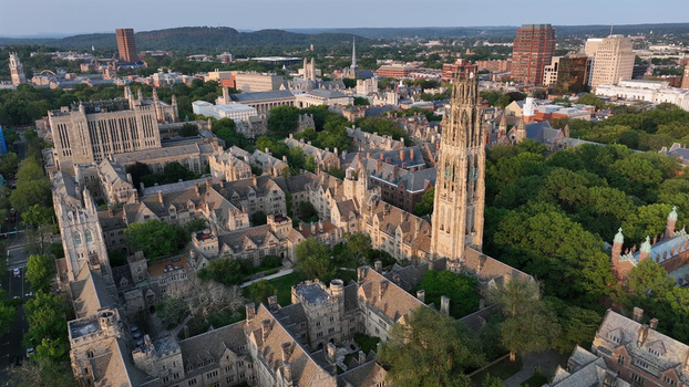 Aerial view of Yale University campus featuring the iconic Harkness Tower historic gothic architecture lush green trees and surrounding urban buildings in New Haven Connecticut United States.