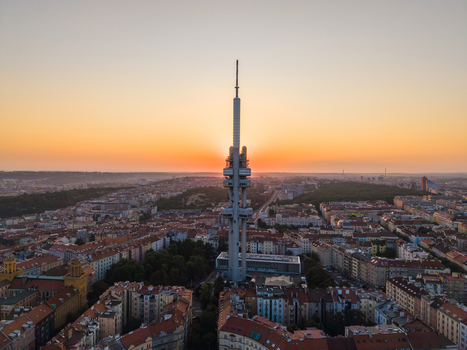 Aerial view of Zizkov Television Tower rising above the historic rooftops and urban landscape at sunset Prague Prague Czechia.