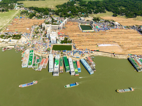 Aerial view of vibrant vessels lining the muddy riverbank against the backdrop of sun baked earth and green trees Charmonai Barisal Division Bangladesh. Aerial view of vibrant vessels lining the muddy riverbank against the backdrop of sun baked earth and green trees Charmonai Barisal Division Bangladesh.