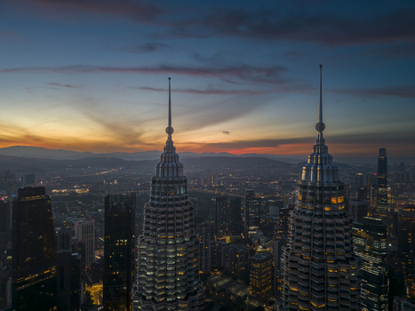 Kuala Lumpur Malaysia 11 March 2026 Aerial view of the Petronas Twin Towers at sunset with the city skyline and mountains in the background under a colorful sky.
