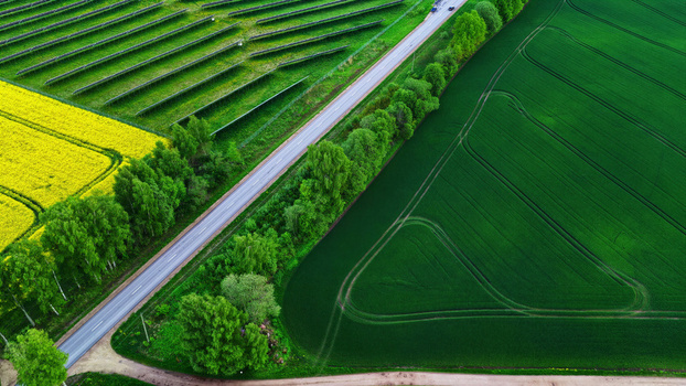 Aerial view of solar panels in a field next to a road and green crops in Latvia. Aerial view of solar panels in a field next to a road and green crops in Latvia.