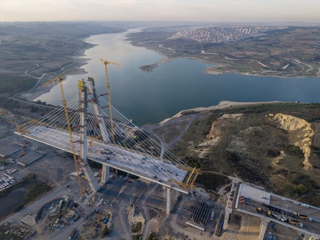 Aerial view of the Sazlidere Bridge construction site with tall cranes cable stayed bridge segments and surrounding reservoir landscape in Istanbul Istanbul Turkiye.