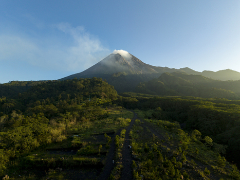 Aerial view of Bunker Kaliadem Merapi and the smoking peak of Mount Merapi surrounded by lush green forests Kecamatan Pakem Daerah Istimewa Yogya Indonesia. Aerial view of Bunker Kaliadem Merapi and the smoking peak of Mount Merapi surrounded by lush green forests Kecamatan Pakem Daerah Istimewa Yogya Indonesia.