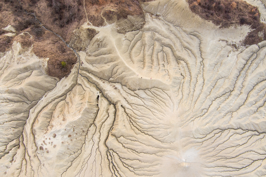 Aerial view of the Mud Volcanoes Paclele Mari showing the unique cracked and eroded landscape with intricate patterns formed by mud flows in Paclele Buzau County Romania.