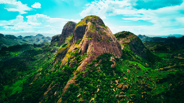 Aerial view of striking rock formations rise majestically amid lush greenery bathed in sunlight under a vibrant sky Antananarivo Madagascar.