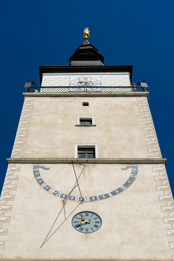 View of the historic City Tower featuring a sundial and clock face against a clear blue sky in Trnava Trnava Region Slovakia. View of the historic City Tower featuring a sundial and clock face against a clear blue sky in Trnava Trnava Region Slovakia.
