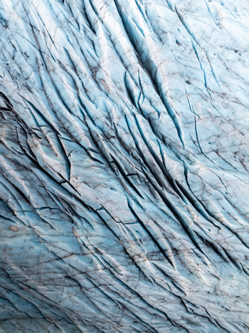 Aerial view of Svinafellsjokull glacier with deep blue ice crevasses and intricate patterns in the frozen surface in Sveitarfelagid Hornafjordur Iceland. Aerial view of Svinafellsjokull glacier with deep blue ice crevasses and intricate patterns in the frozen surface in Sveitarfelagid Hornafjordur Iceland.