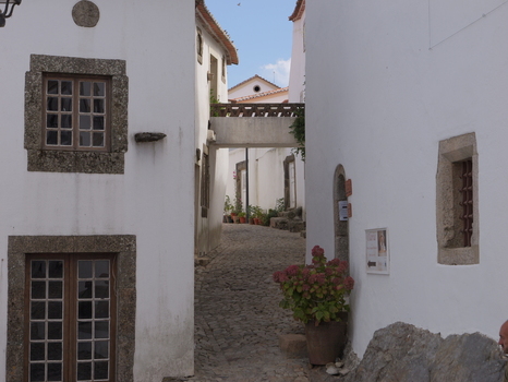 View of a narrow cobblestone street in the historic village of Marvao with traditional white washed houses stone framed windows and a small bridge in Marvao Portalegre District Portugal. View of a narrow cobblestone street in the historic village of Marvao with traditional white washed houses stone framed windows and a small bridge in Marvao Portalegre District Portugal.