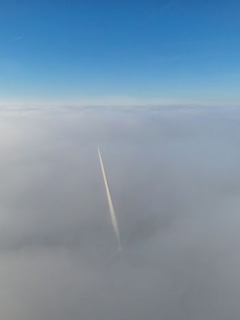 Aerial view of a solitary contrail slicing through a sea of clouds the town hidden below the cottony expanse Ch&acirc;teaudun Centre Val de Loire France.