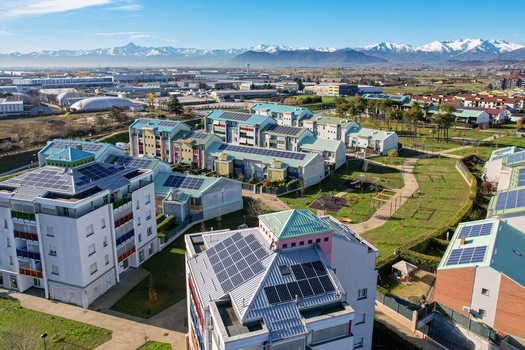 Aerial view of modern residential buildings with solar panels on rooftops and green parks with the snow capped Alps in the background Grugliasco Piedmont Italy. Aerial view of modern residential buildings with solar panels on rooftops and green parks with the snow capped Alps in the background Grugliasco Piedmont Italy.