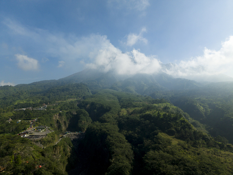 Aerial view of Tambang Pasir Merapi Kali Gendol Sand Mine and lush slopes of Mount Merapi under a blue sky Kecamatan Cangkringan Daerah Istimewa Yogya Indonesia. Aerial view of Tambang Pasir Merapi Kali Gendol Sand Mine and lush slopes of Mount Merapi under a blue sky Kecamatan Cangkringan Daerah Istimewa Yogya Indonesia.