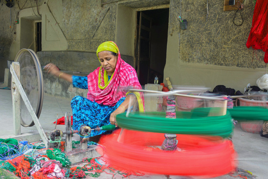 Joypurhat Rajshahi Division Bangladesh 22 September 2026 View of a woman spinning colorful green and red yarn on a traditional charkha in a rural workshop. Joypurhat Rajshahi Division Bangladesh 22 September 2026 View of a woman spinning colorful green and red yarn on a traditional charkha in a rural workshop.
