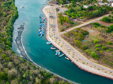 Aerial view of Punta Perula featuring a scenic pier with docked boats along the turquoise water surrounded by lush coastal vegetation in Punta Perula Jalisco Mexico. Aerial view of Punta Perula featuring a scenic pier with docked boats along the turquoise water surrounded by lush coastal vegetation in Punta Perula Jalisco Mexico.
