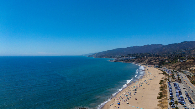 Aerial view of Will Rogers State Beach featuring the sandy coastline Pacific Ocean coastal highway and mountains in Los Angeles California United States.