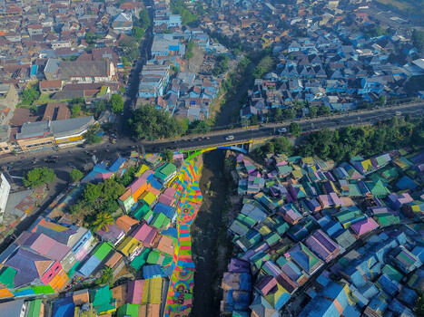 Aerial view of Kampung Warna Warni Jodipan featuring vibrant multi colored houses along the riverbank with a bridge crossing in Kecamatan Blimbing Jawa Timur Indonesia. Aerial view of Kampung Warna Warni Jodipan featuring vibrant multi colored houses along the riverbank with a bridge crossing in Kecamatan Blimbing Jawa Timur Indonesia.