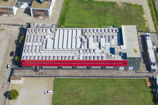 Aerial view of a modern datacenter building featuring a flat roof densely packed with numerous HVAC cooling units and a prominent red facade section Arezzo Tuscany Italy. Aerial view of a modern datacenter building featuring a flat roof densely packed with numerous HVAC cooling units and a prominent red facade section Arezzo Tuscany Italy.