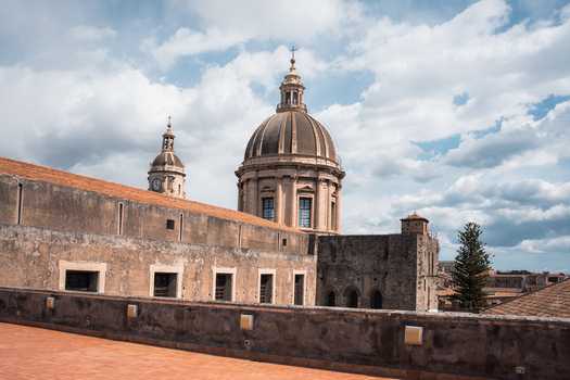 View of the dome of a historic cathedral rises above the rooftops contrasting against the cloudy sky a timeless scene of architectural beauty Taormina Sicily Italy. View of the dome of a historic cathedral rises above the rooftops contrasting against the cloudy sky a timeless scene of architectural beauty Taormina Sicily Italy.