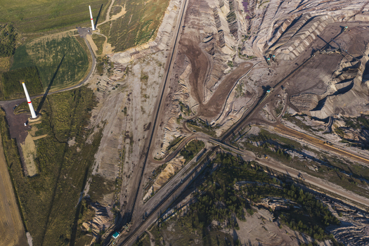 Aerial view of the Schleenhain lignite open cast mine featuring deep excavation pits industrial conveyor paths and wind turbines in Zwenkau Saxony Germany.