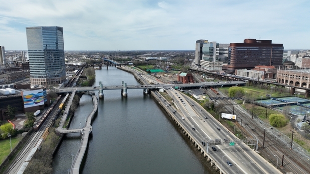 Aerial view of the Schuylkill River reflecting the sky flowing under bridges and past modern buildings with a highway bustling with traffic Philadelphia Pennsylvania United States.