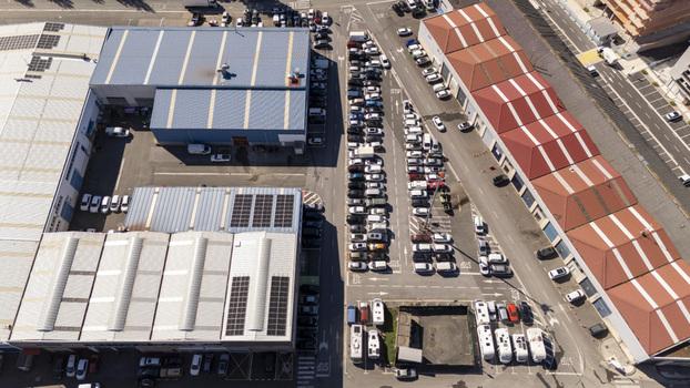 Aerial view of industrial buildings with solar panels and a busy parking lot filled with cars in an urban area in Zumaia Basque Country Spain.