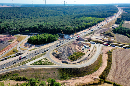Aerial view of a highway construction site with trucks cranes and earthworks near a dense forest in Hochstadt Bavaria Germany. Aerial view of a highway construction site with trucks cranes and earthworks near a dense forest in Hochstadt Bavaria Germany.