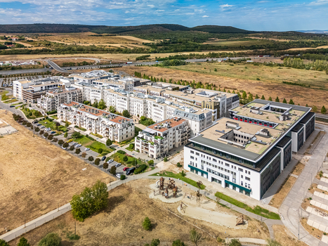 Aerial view of a modern residential complex beside the M0 highway in Biatorbagy Hungary surrounded by apartment blocks roads dry fields and wooded hills. Aerial view of a modern residential complex beside the M0 highway in Biatorbagy Hungary surrounded by apartment blocks roads dry fields and wooded hills.