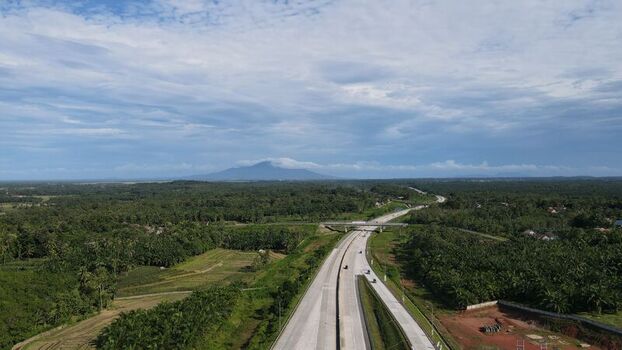 Aerial view of Jalan Tol Terbanggi Besar Pematang Panggang Kayu Agung highway through green landscape and palm oil plantations in Kecamatan Lempuing Jaya Sumatera Selatan Indonesia. Aerial view of Jalan Tol Terbanggi Besar Pematang Panggang Kayu Agung highway through green landscape and palm oil plantations in Kecamatan Lempuing Jaya Sumatera Selatan Indonesia.