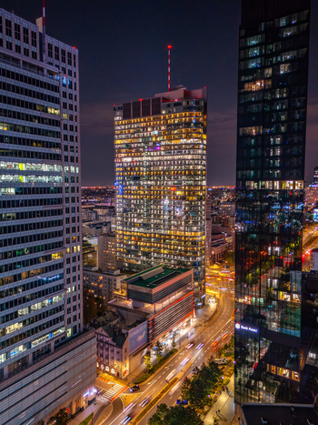 Aerial view of modern skyscrapers with illuminated windows and light trails from traffic on the city streets at night in Poland. Aerial view of modern skyscrapers with illuminated windows and light trails from traffic on the city streets at night in Poland.