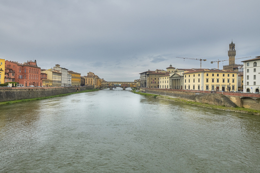 Florence Italy 05 May 2022 View of the Ponte Vecchio bridge spanning the Arno River with historic buildings and the Palazzo Vecchio tower in the background under a cloudy sky. Florence Italy 05 May 2022 View of the Ponte Vecchio bridge spanning the Arno River with historic buildings and the Palazzo Vecchio tower in the background under a cloudy sky.