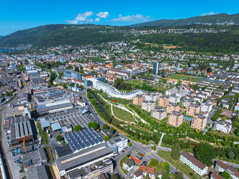 Aerial view of the modern Swatch headquarters building with its unique curved architecture industrial zones and residential areas in Biel Bienne Canton of Bern Switzerland.